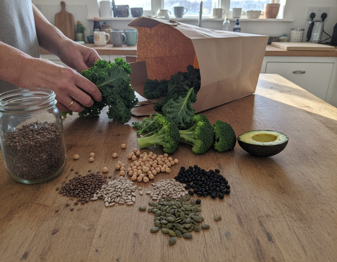 Broccoli, kale, lentils, beans and seeds being unpacked on a kitchen island