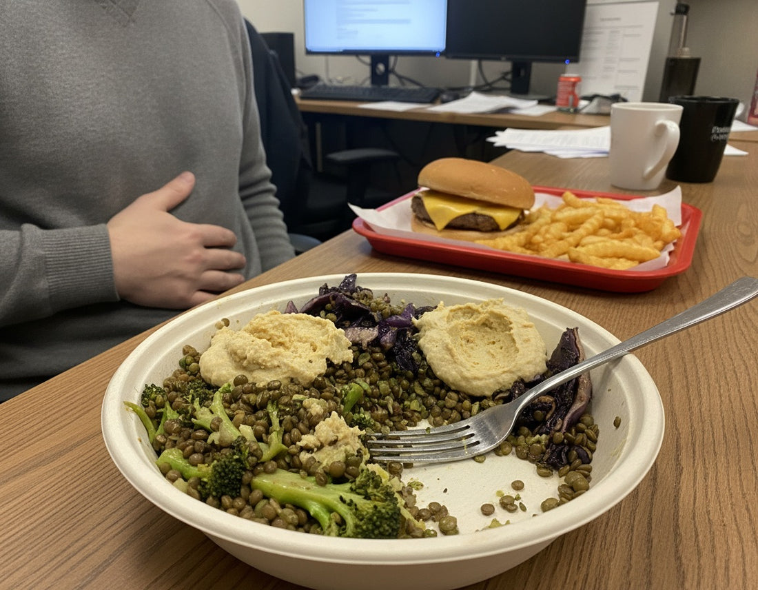 A half-eaten lentil and broccoli bowl, with a coworker's burger and fries behind it